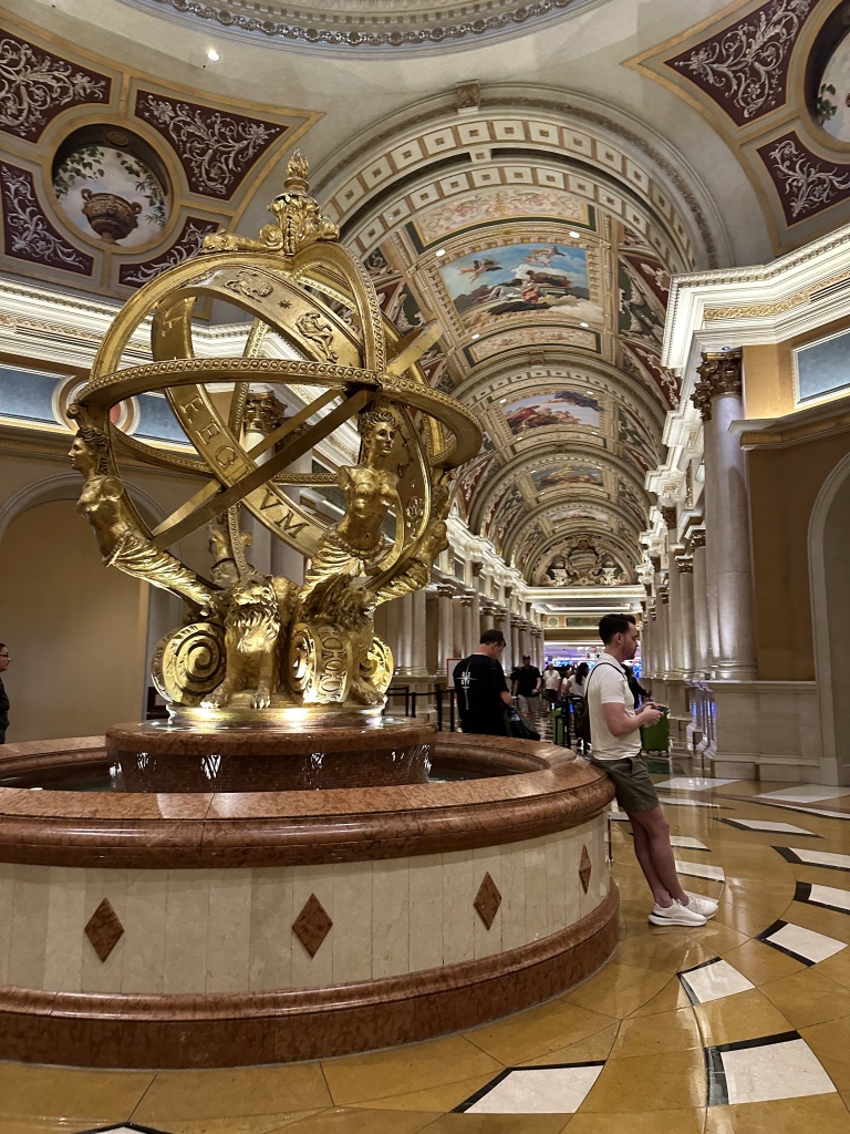The lobby of the Venetian hotel.  Very grand with painted arched ceilings, large gold globe sculpture in foreground.